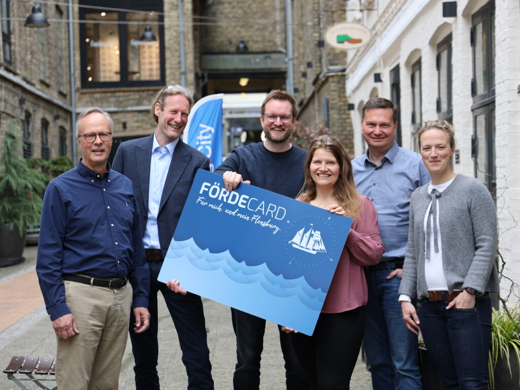 Die Verantwortlichen der FördeCARD halten eine überdimensionale FördeCARD in die Kamera.